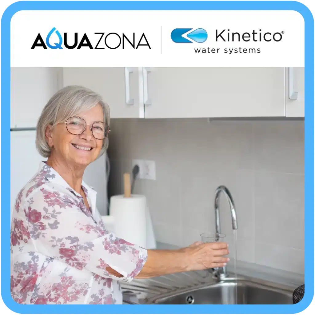 homeowner smiling, standing at her kitchen sink while using water filtration dispenser