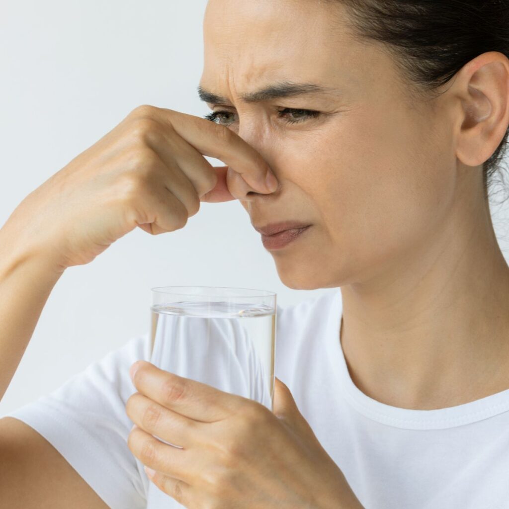 woman smelling bad odor on water