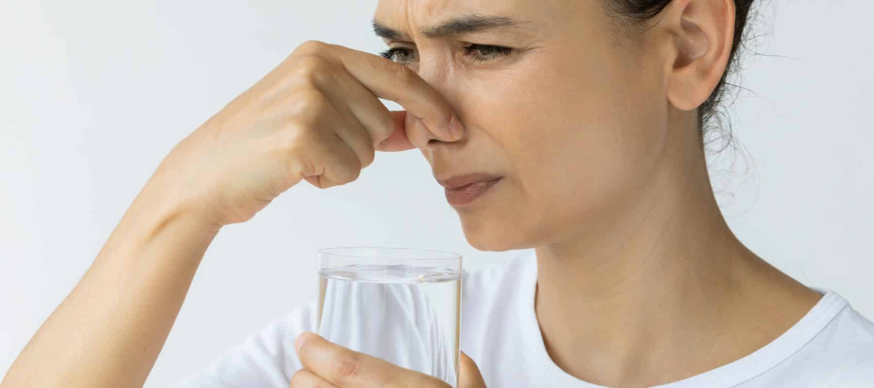 woman smelling bad odor on water