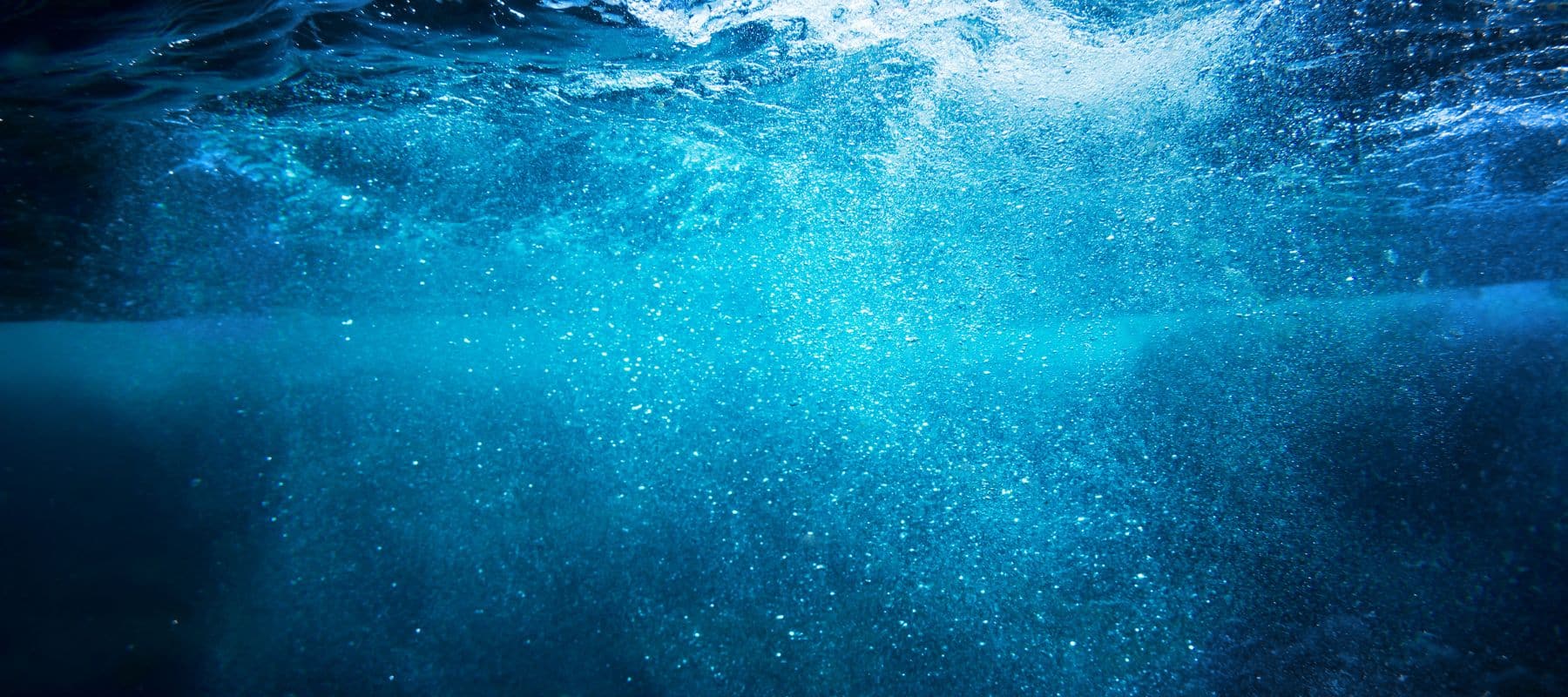 An underwater view showing bubbles rising to the surface in a deep blue environment