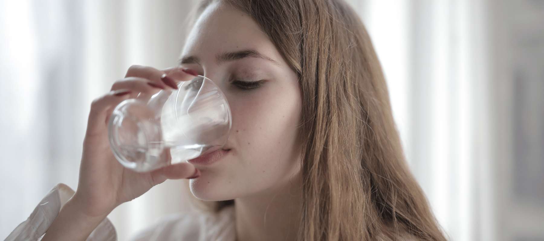 closeup of a young woman drinking a glass of water